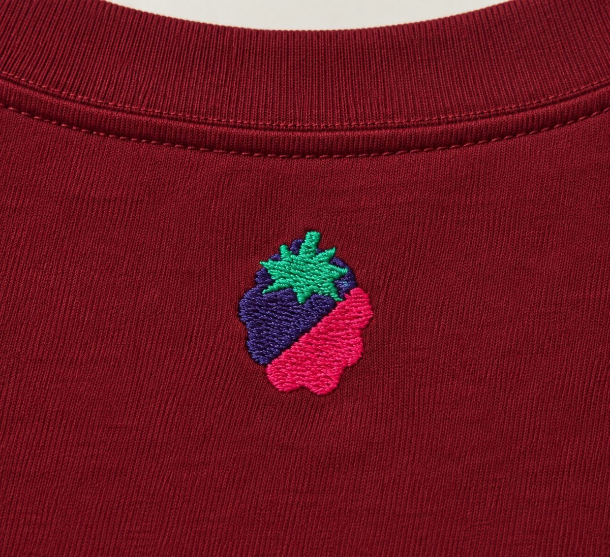 Gros plan sur la broderie Raizberry, sur un t-shirt bordeaux.
